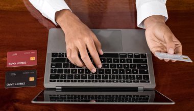 İş adamının elinde bir kredi kartı var ve online alışveriş ve internet ödemeleri için bir laptop kullanıyor..
