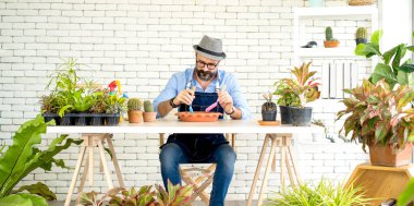 Bıyıklı, yaşlı ve yakışıklı bir adam ağaç bakımıyla mutlu olur. Evde bahçıvanlık hobisi. Emeklilikten sonra mutlu yaşamak. Doğa ve çevre kavramları.