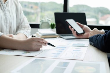 İki iş lideri çizelgeler, finansal grafikler hakkında konuşuyor. Sonuçları gösteren planlama stratejilerini analiz ediyor ve hesaplıyor. Ticari başarı oluşturma süreçlerini de..