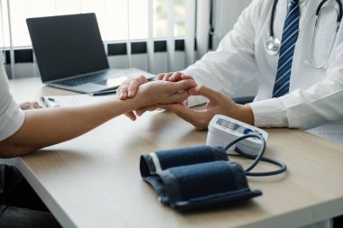 Erkek doktor, hastanın nabzını ve kalp atışlarını ölçer ve sağlık bakımını yakından tartışır. Tıbbi ve sağlık hizmetleri kavramları.