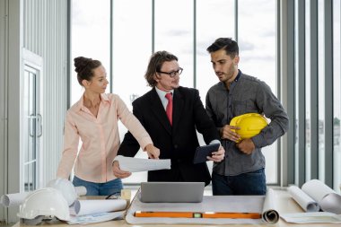 Erkek ve kadın mühendisler ve mimarlardan oluşan bir ekip, çalışma ekibi, inşaat planlarını tartışıyor ve çiziyor, baskı yapıyor, inşaat alanlarında yazıyor..