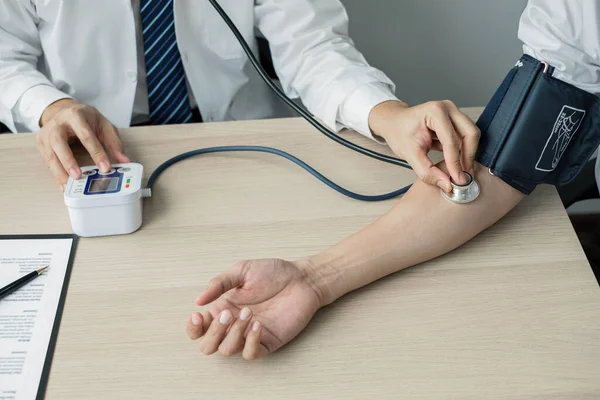 Erkek doktorlar kan basıncını ölçtü, hasta kalp atışlarını inceledi ve sağlık hizmetleri hakkında yakından konuştu. Tıbbi ve sağlık hizmetleri kavramları.