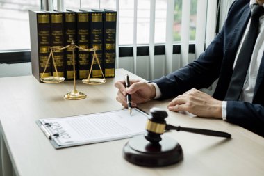 Profesyonel erkek avukatlar bir hukuk bürosunda çalışır. Teraziler, adalet terazileri, yargıç tokmağı ve dava belgeleri vardır. Hukuk ve adalet kavramları.