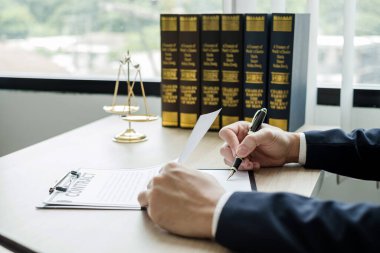 Profesyonel erkek avukatlar bir hukuk bürosunda çalışır. Teraziler, adalet terazileri, yargıç tokmağı ve dava belgeleri vardır. Hukuk ve adalet kavramları.