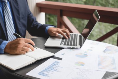 Evde çalışan ve yatırımlarının sonuçlarını gösteren mali grafikleri hesaplayan iş adamının el emeği, iş büyümesinin adımlarını planlamak..