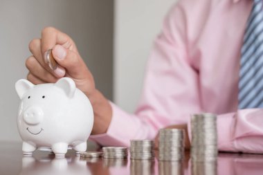 Bir işadamının eli kumbaraya bozuk para koyar, madeni paralarla para biriktirir, başarılı bir büyüme işine adım atar ve emeklilik kavramı için tasarruf eder..