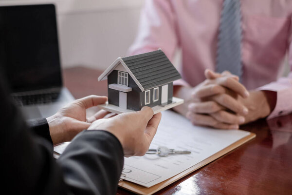 Real estate agent broker hand over the home to the new owner after completing the signing according to agreement renting a house and buy house insurance Home insurance concept.