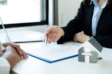 Ev modeli olan bir emlakçı ev sigortası almak için müşterilerle konuşuyor. Ev sigortası kavramı.