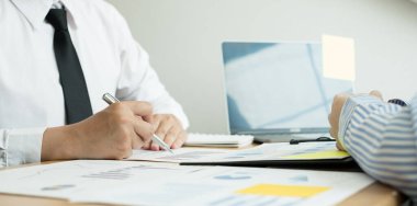 İki iş lideri çizelgeler, finansal grafikler hakkında konuşuyor. Sonuçları gösteren planlama stratejilerini analiz ediyor ve hesaplıyor. Ticari başarı oluşturma süreçlerini de..