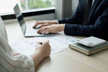 İki iş lideri çizelgeler, finansal grafikler hakkında konuşuyor. Sonuçları gösteren planlama stratejilerini analiz ediyor ve hesaplıyor. Ticari başarı oluşturma süreçlerini de..