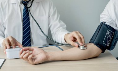 Erkek doktorlar kan basıncını ölçtü, hasta kalp atışlarını inceledi ve sağlık hizmetleri hakkında yakından konuştu. Tıbbi ve sağlık hizmetleri kavramları.