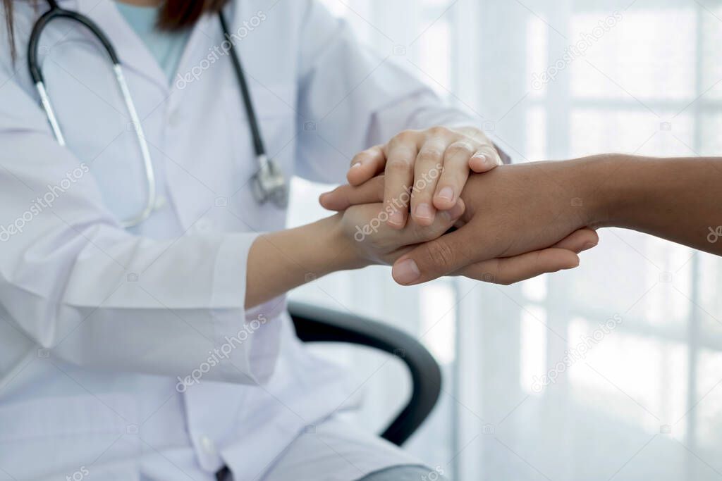 The female doctor uses a friendly hand to hold the patient's hand to give confidence and show care about health care. Medical concepts and good health.