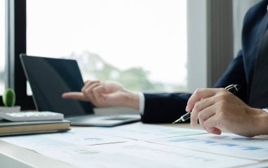 İş adamının eli masalarında oturup yatırımlarıyla ilgili sonuçları gösteren finansal grafikleri hesaplıyor, başarılı bir iş büyüme süreci planlıyor.