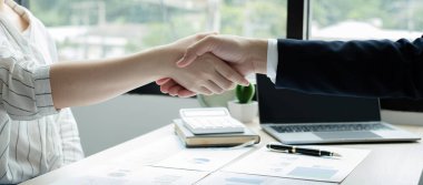 İki iş lideri çizelgeler, finansal grafikler hakkında konuşuyor. Sonuçları gösteren planlama stratejilerini analiz ediyor ve hesaplıyor. İş başarısı oluşturma süreçleri ve el sıkışıyor..