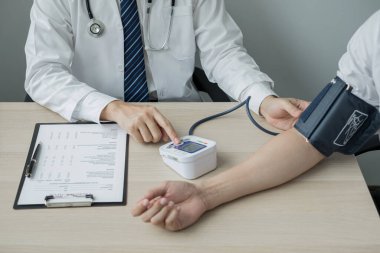 Erkek doktorlar kan basıncını ölçtü, hasta kalp atışlarını inceledi ve sağlık hizmetleri hakkında yakından konuştu. Tıbbi ve sağlık hizmetleri kavramları.