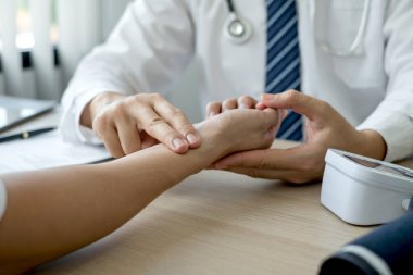 Erkek doktor, hastanın nabzını ve kalp atışlarını ölçer ve sağlık bakımını yakından tartışır. Tıbbi ve sağlık hizmetleri kavramları.