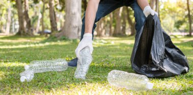 Çöp toplama, insanların elleri plastik şişeleri toplar, çöpleri parkları temizlemek, kirlilikten kaçınmak, çevreye ve ekosisteme dost olmak için siyah çöp torbalarına koyar..