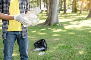 Adamın elleri plastik şişeleri topluyor, çöpleri siyah çöp torbalarına doldurup parkları temizliyor, kirlilikten kaçınıyor, çevreye ve ekosisteme dost oluyor..