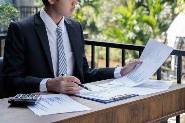 Genç iş adamı finansal piyasa analisti masalarında oturuyor ve başarılı iş büyümesi sürecini planlayan yatırımlarının sonuçlarını gösteren mali grafikleri hesaplıyor.