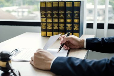 Profesyonel erkek avukatlar bir hukuk bürosunda çalışır. Teraziler, adalet terazileri, yargıç tokmağı ve dava belgeleri vardır. Hukuk ve adalet kavramları.
