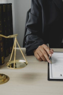 Profesyonel kadın avukatlar bir hukuk bürosunda çalışır. Teraziler, adalet terazileri, yargıç tokmağı ve dava belgeleri vardır. Hukuk ve adalet kavramları.