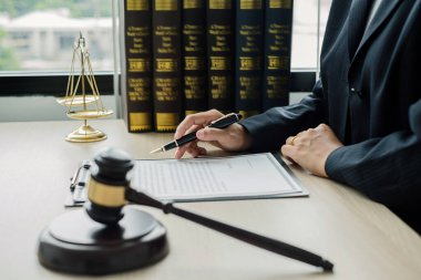 Profesyonel kadın avukatlar bir hukuk bürosunda çalışır. Teraziler, adalet terazileri, yargıç tokmağı ve dava belgeleri vardır. Hukuk ve adalet kavramları.