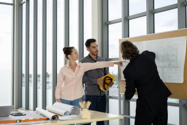 Erkek ve kadın mühendisler ve mimarlardan oluşan bir ekip, çalışma ekibi, inşaat planlarını tartışıyor ve çiziyor, baskı yapıyor, inşaat alanlarında yazıyor..