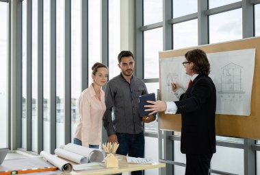 Erkek ve kadın mühendisler ve mimarlardan oluşan bir ekip, çalışma ekibi, inşaat planlarını tartışıyor ve çiziyor, baskı yapıyor, inşaat alanlarında yazıyor..