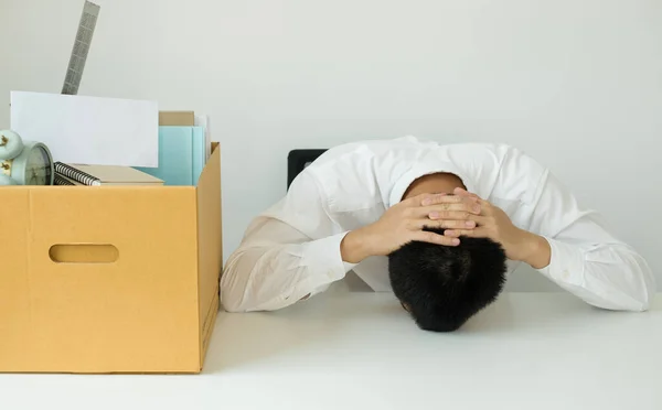 A male office worker is unhappy with being fired from a company packing things into cardboard boxes. The young man was stressed and disappointed by being fired. concept of layoffs and unemployment.