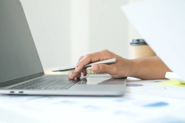 Finans sektöründe çalışan bir kadın evinde oturup yatırımlarının sonuçlarını gösteren mali grafikleri hesaplar ve iş büyümesinin adımlarını planlar..