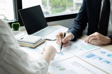 İki iş lideri çizelgeler, finansal grafikler hakkında konuşuyor. Sonuçları gösteren planlama stratejilerini analiz ediyor ve hesaplıyor. Ticari başarı oluşturma süreçlerini de..