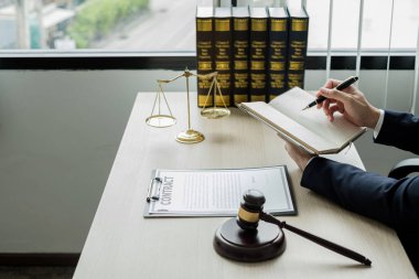 Profesyonel erkek avukatlar bir hukuk bürosunda çalışır. Teraziler, adalet terazileri, yargıç tokmağı ve dava belgeleri vardır. Hukuk ve adalet kavramları.