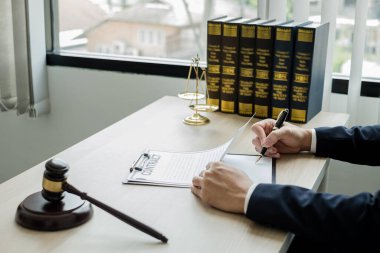 Profesyonel erkek avukatlar bir hukuk bürosunda çalışır. Teraziler, adalet terazileri, yargıç tokmağı ve dava belgeleri vardır. Hukuk ve adalet kavramları.