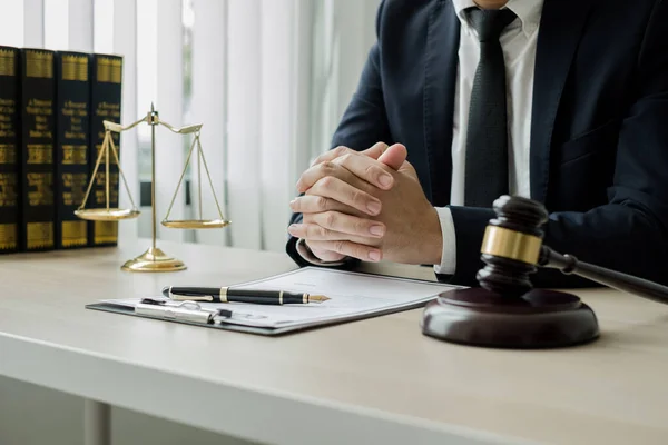Profesyonel erkek avukatlar bir hukuk bürosunda çalışır. Teraziler, adalet terazileri, yargıç tokmağı ve dava belgeleri vardır. Hukuk ve adalet kavramları.