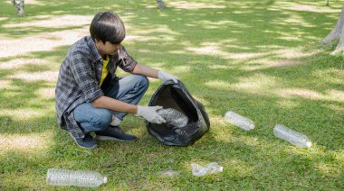 Genç Asyalı erkekler, çöpçüler plastik şişeleri topluyor, çöpleri siyah çöp torbalarına dolduruyor, parkları temizliyor, kirlilikten kaçınıyor, çevreye ve ekosisteme dost oluyor..