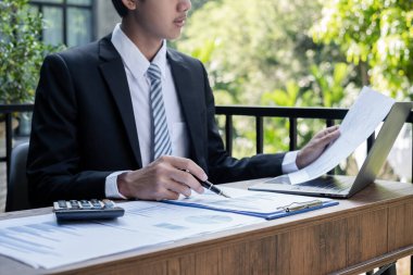 Genç iş adamı finansal piyasa analisti masalarında oturuyor ve başarılı iş büyümesi sürecini planlayan yatırımlarının sonuçlarını gösteren mali grafikleri hesaplıyor.