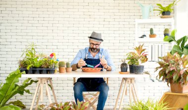 Bıyıklı, yaşlı ve yakışıklı bir adam ağaç bakımıyla mutlu olur. Evde bahçıvanlık hobisi. Emeklilikten sonra mutlu yaşamak. Doğa ve çevre kavramları.