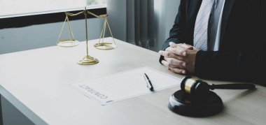 Profesyonel erkek avukatlar bir hukuk bürosunda çalışır. Teraziler, adalet terazileri, yargıç tokmağı ve dava belgeleri vardır. Hukuk ve adalet kavramları.