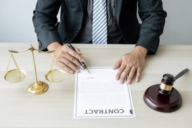 Profesyonel erkek avukatlar bir hukuk bürosunda çalışır. Teraziler, adalet terazileri, yargıç tokmağı ve dava belgeleri vardır. Hukuk ve adalet kavramları.