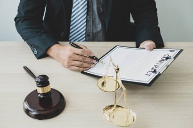 Profesyonel erkek avukatlar bir hukuk bürosunda çalışır. Teraziler, adalet terazileri, yargıç tokmağı ve dava belgeleri vardır. Hukuk ve adalet kavramları.