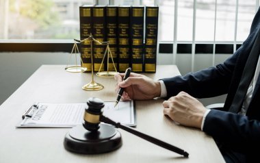 Profesyonel erkek avukatlar bir hukuk bürosunda çalışır. Teraziler, adalet terazileri, yargıç tokmağı ve dava belgeleri vardır. Hukuk ve adalet kavramları.