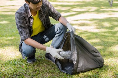 Genç Asyalı erkekler, çöpçüler plastik şişeleri topluyor, çöpleri siyah çöp torbalarına dolduruyor, parkları temizliyor, kirlilikten kaçınıyor, çevreye ve ekosisteme dost oluyor..