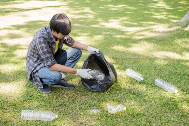 Genç Asyalı erkekler, çöpçüler plastik şişeleri topluyor, çöpleri siyah çöp torbalarına dolduruyor, parkları temizliyor, kirlilikten kaçınıyor, çevreye ve ekosisteme dost oluyor..