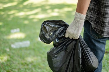 Çöp toplama, insanların elleri plastik şişeleri toplar, çöpleri parkları temizlemek, kirlilikten kaçınmak, çevreye ve ekosisteme dost olmak için siyah çöp torbalarına koyar..
