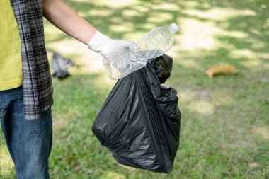 Çöp toplama, insanların elleri plastik şişeleri toplar, çöpleri parkları temizlemek, kirlilikten kaçınmak, çevreye ve ekosisteme dost olmak için siyah çöp torbalarına koyar..
