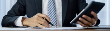 Genç iş adamı finansal piyasa analisti masalarında oturuyor ve başarılı iş büyümesi sürecini planlayan yatırımlarının sonuçlarını gösteren mali grafikleri hesaplıyor.