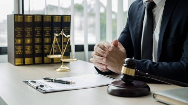 Profesyonel erkek avukatlar bir hukuk bürosunda çalışır. Teraziler, adalet terazileri, yargıç tokmağı ve dava belgeleri vardır. Hukuk ve adalet kavramları.