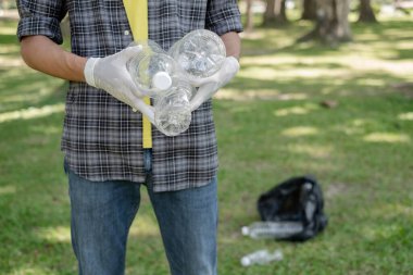 Adamın elleri plastik şişeleri topluyor, çöpleri siyah çöp torbalarına doldurup parkları temizliyor, kirlilikten kaçınıyor, çevreye ve ekosisteme dost oluyor..