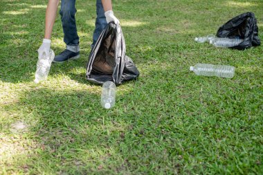 Adamın elleri plastik şişeleri topluyor, çöpleri siyah çöp torbalarına doldurup parkları temizliyor, kirlilikten kaçınıyor, çevreye ve ekosisteme dost oluyor..