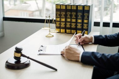 Profesyonel erkek avukatlar bir hukuk bürosunda çalışır. Teraziler, adalet terazileri, yargıç tokmağı ve dava belgeleri vardır. Hukuk ve adalet kavramları.